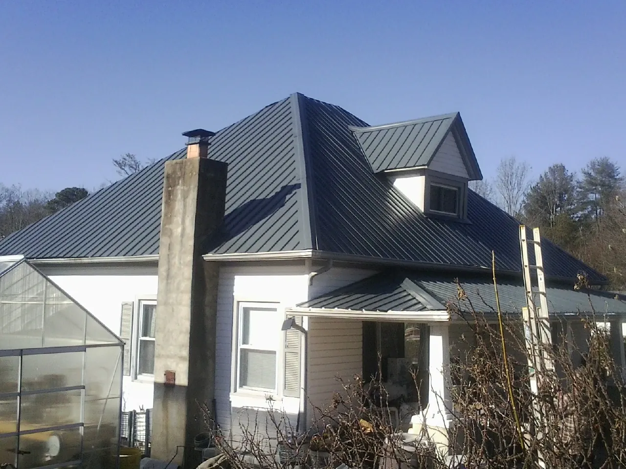 Dark blue standing seam metal roof on a white farmhouse with dormer — Slate & Tile Roof Repair by Roofing Brothers in Westernville