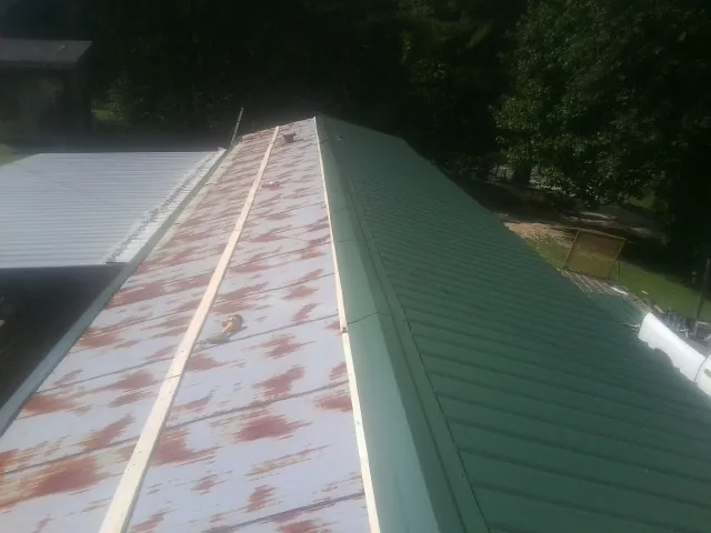 Old rusted panels beside newly installed green metal roofing — Wind Damage Roof Repair by Roofing Brothers in Westernville