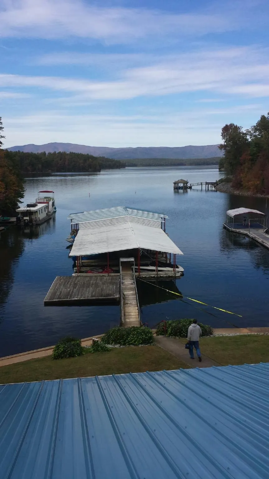 View across a lake from a newly installed blue metal roof in Westernville
