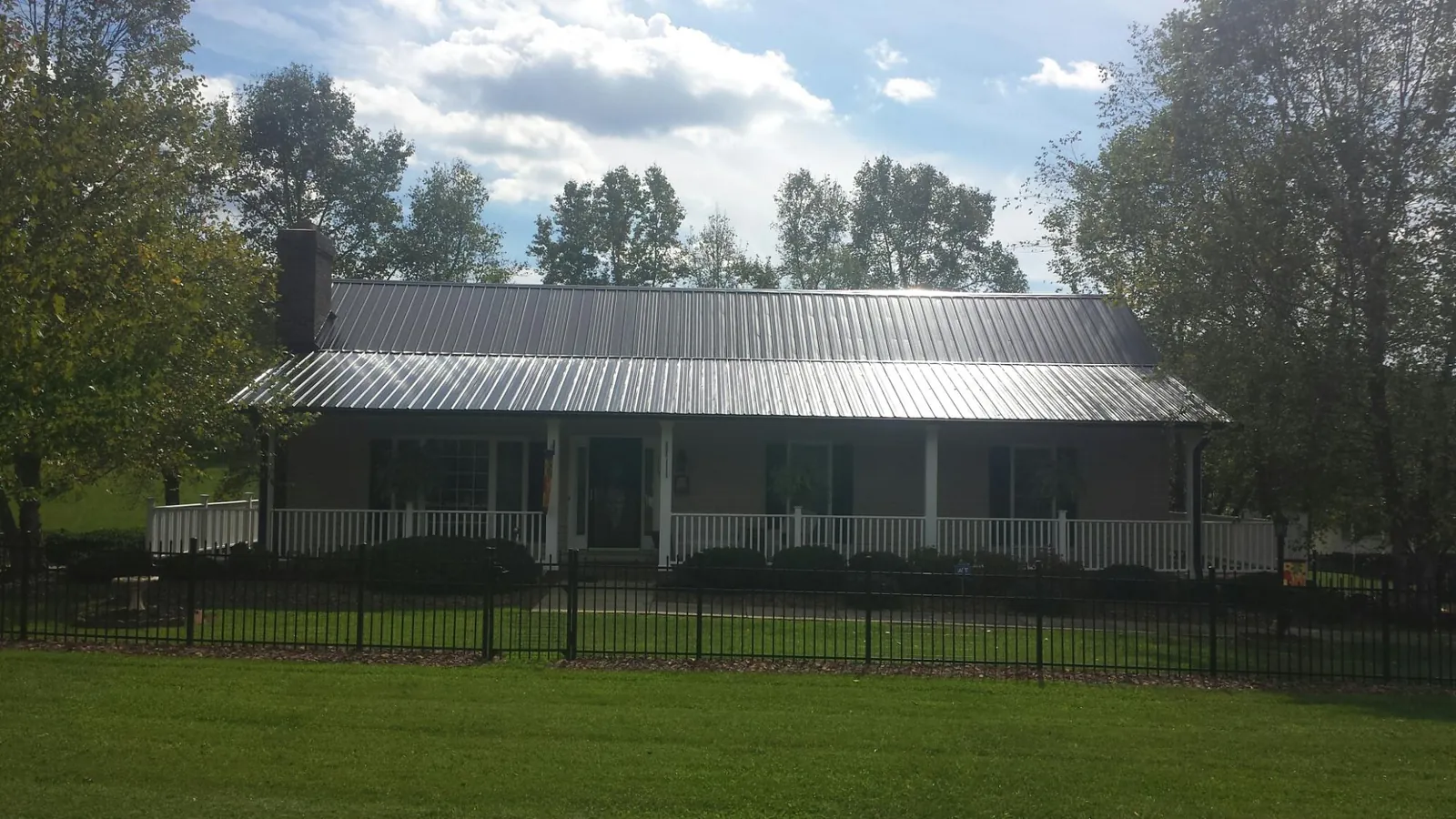 Gray metal roof on a brick ranch with a full width front porch — Gutter Guard Installation work by our crew in Westernville