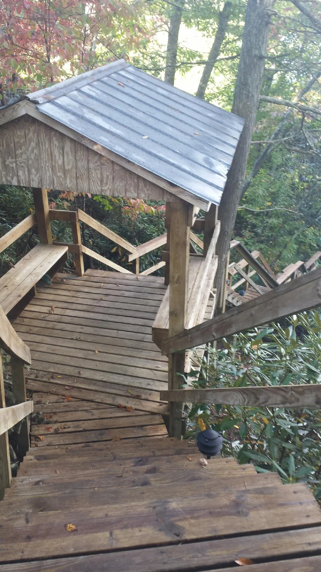 Metal roofed shelter over wooden steps on a wooded walkway — Skylight Repair & Installation work by our crew in Westernville