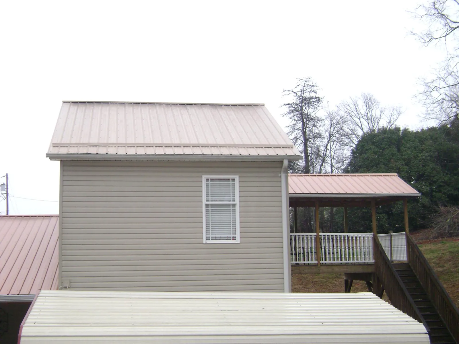 Tan metal roofs on a two story addition and attached porch, from a Roof Replacement job in Westernville
