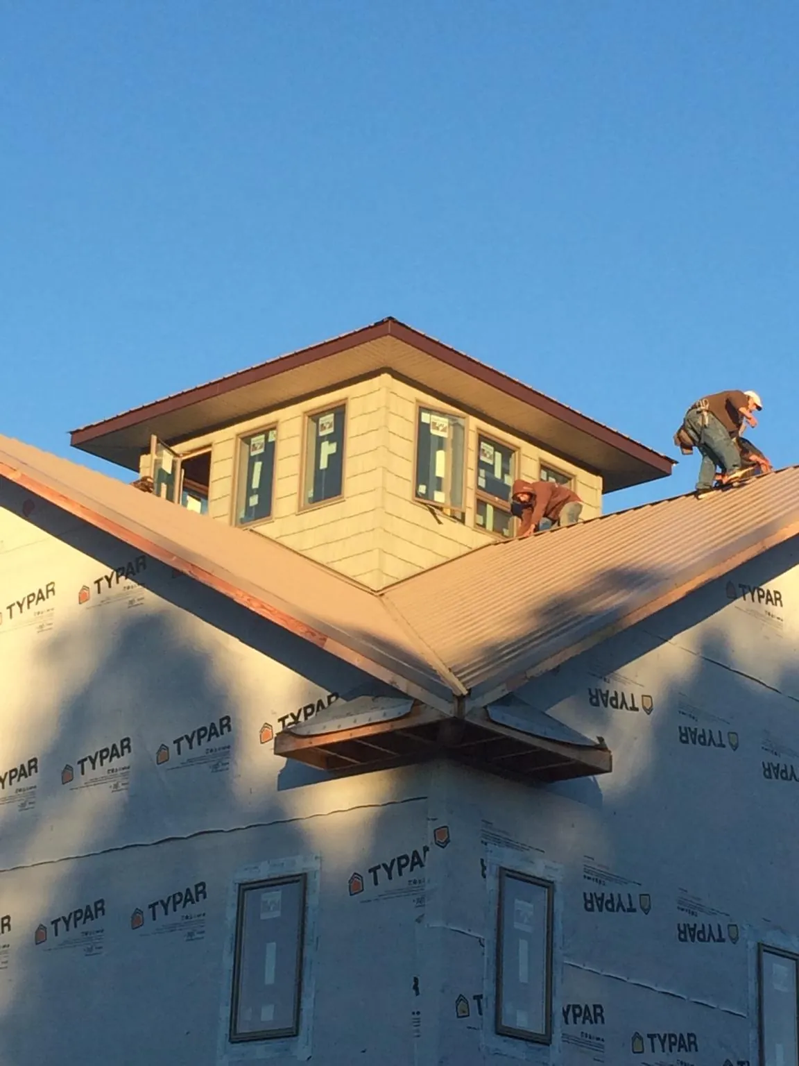 Roofers working around a rooftop cupola on a new metal roof at sunset — Roof Waterproofing in Westernville by Roofing Brothers